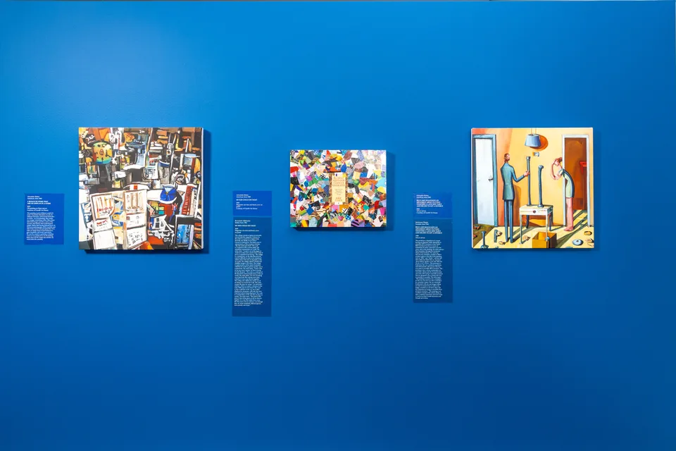 Three works hang side by side on a blue gallery wall: a store-display painting, a collage, and a painting of two figures in a yellow room.