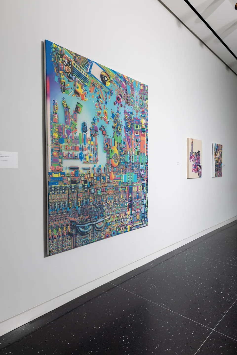 Three colorful paintings installed along a white gallery wall, with a large turquoise painting in the foreground.