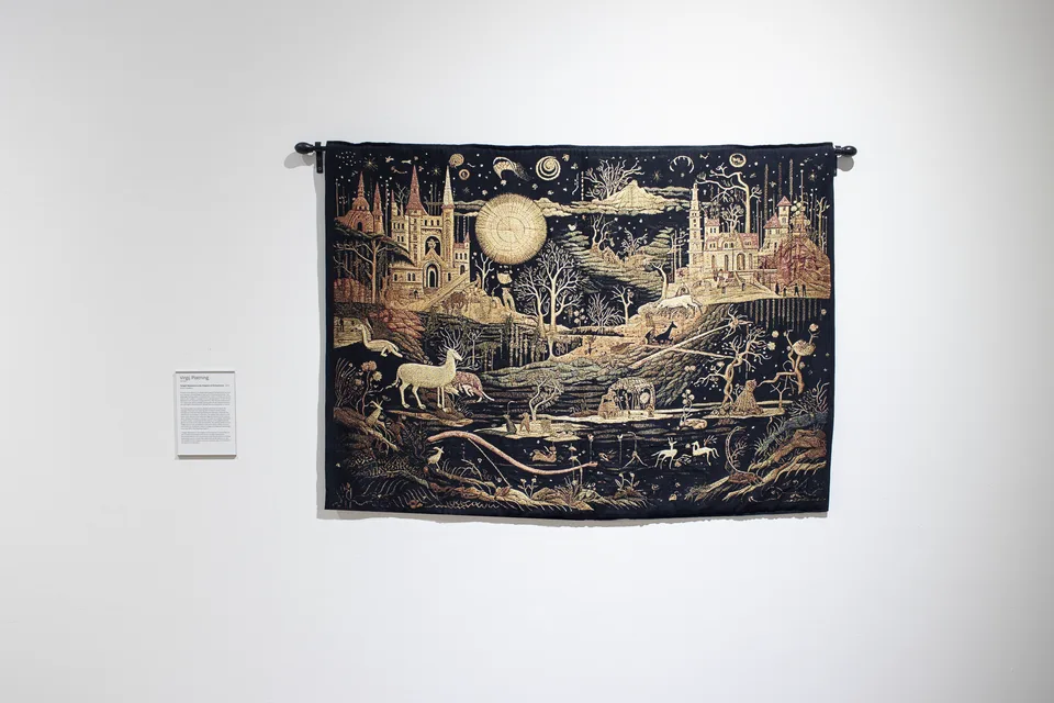 A wider view of the tapestry shows castles and a golden orb above pale animals, tree branches and winding bands.