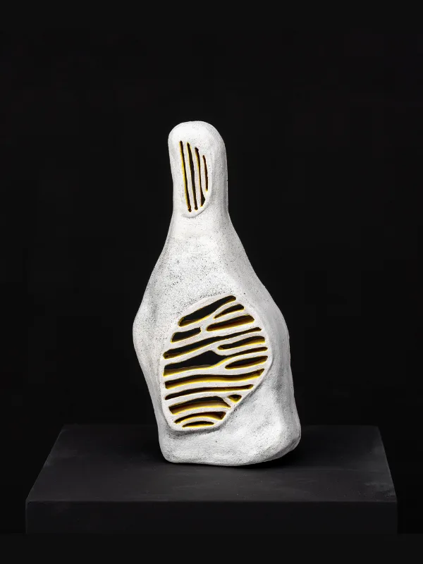 A white ceramic bottle-like form with an exposed ribbed interior.