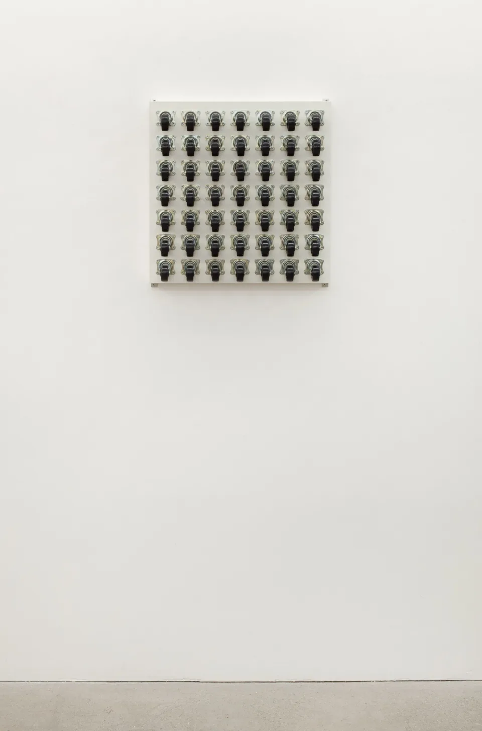 A small grid of caster wheels shown on a large white wall