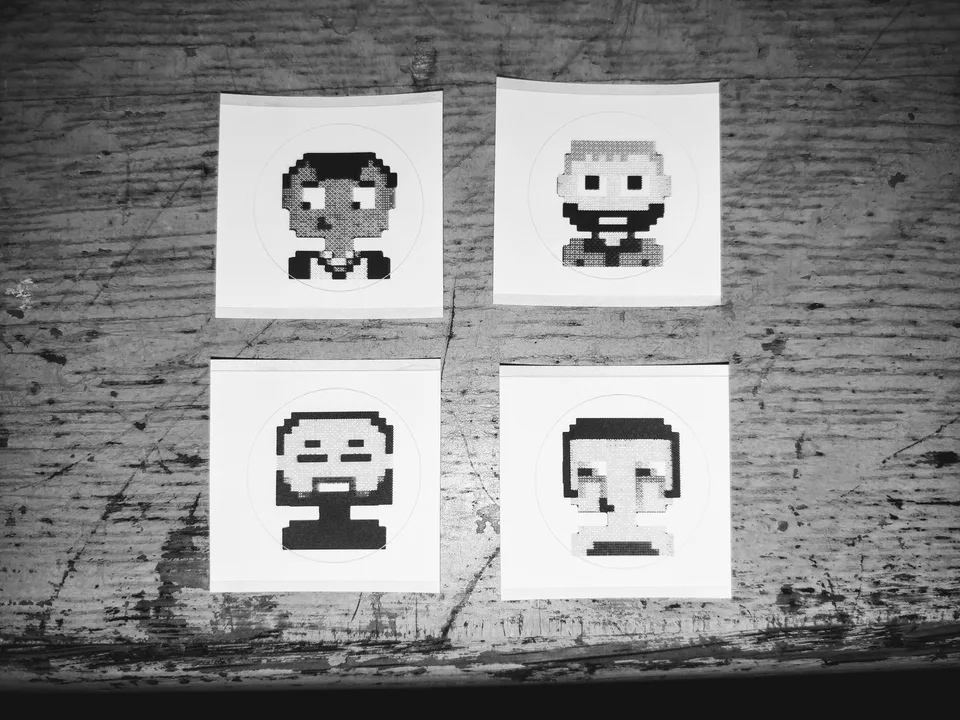 Four small black-and-white pixel portraits printed on square sheets for TokenArt