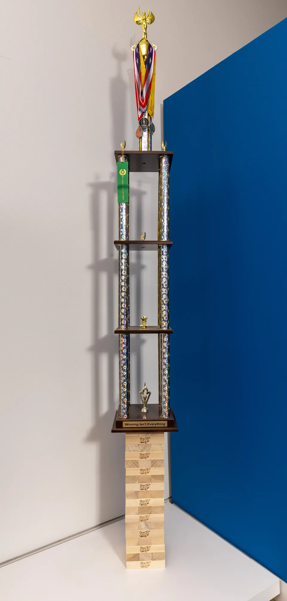 A tall multi-tiered trophy topped with medals balances on a tower of wooden game blocks.