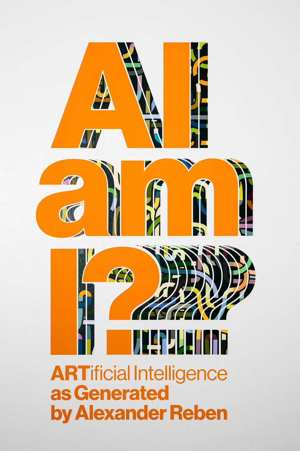 Orange exhibition title lettering on a white wall.