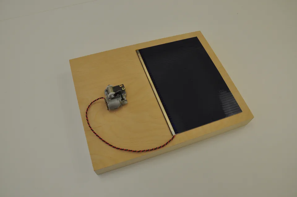 A framed solar panel connected to a music-box mechanism
